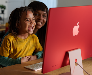 Eine Familie sieht gemeinsam eine Serie auf dem iMac und lacht.